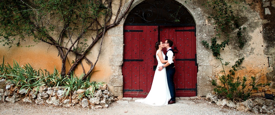 Des mariés s'embrassent devant une porte ancienne